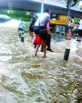 武汉暴雨路面被淹男子蹚水过街